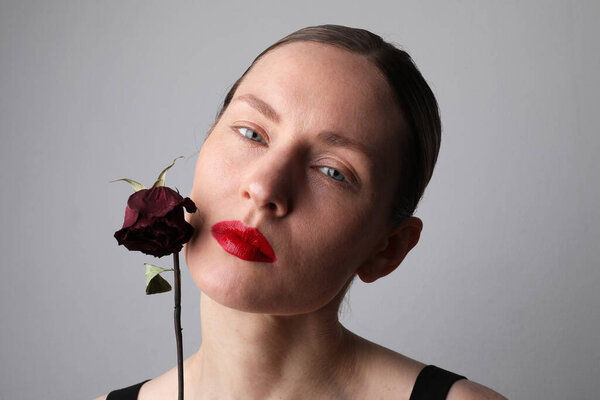Anti ageing treatment. Woman with dry rose posing on white background. High quality photo.
