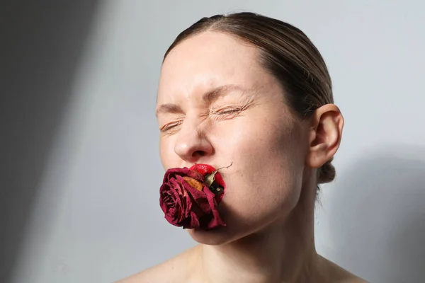 Крупним планом портрет молодої жінки з сухою трояндою тримається в губах. Краса шкіри . — стокове фото