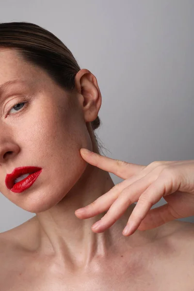 Вертикальний крупним планом молода жінка з ідеальною шкірою і червоними губами позує в приміщенні . — стокове фото