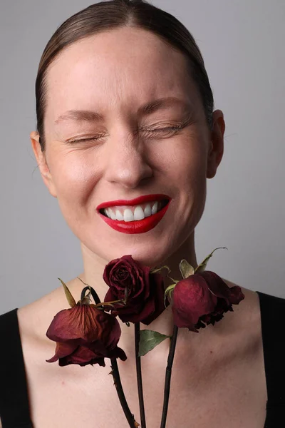 Вертикальний портрет оптимістичної жінки з сухими трояндами позує на білому тлі . — стокове фото