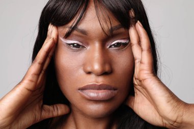 Close-up of beautiful African young woman is touching her face. Mind set.