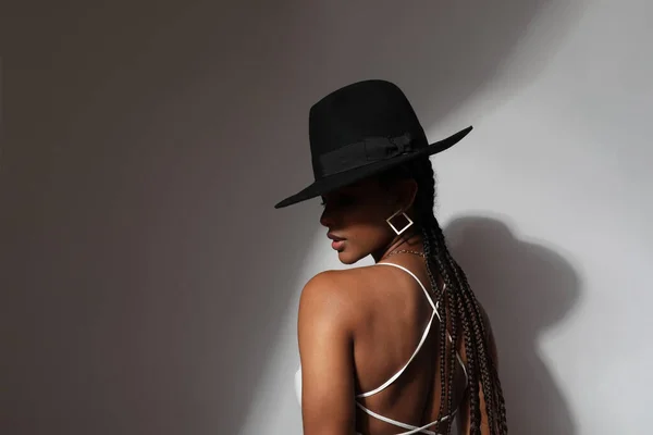 Portrait of stylish African young woman wears black hat posing on white wall. — стокове фото