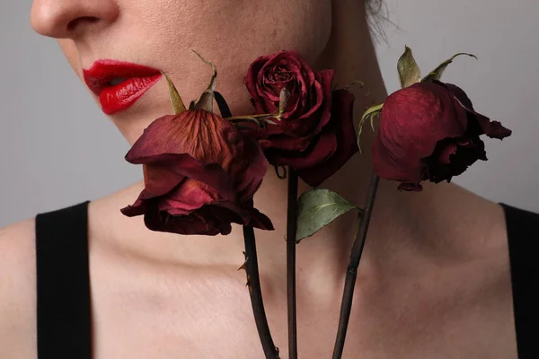 Обрізаний портрет жінки з червоними губами і сухими трояндами позує на білій стіні . — стокове фото
