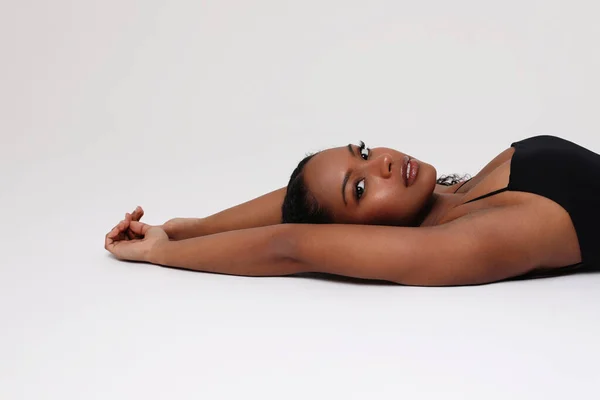 Позитивна темношкіра молода жінка позує в приміщенні. Догляд за тілом та шкірою. Ізольовані . — стокове фото