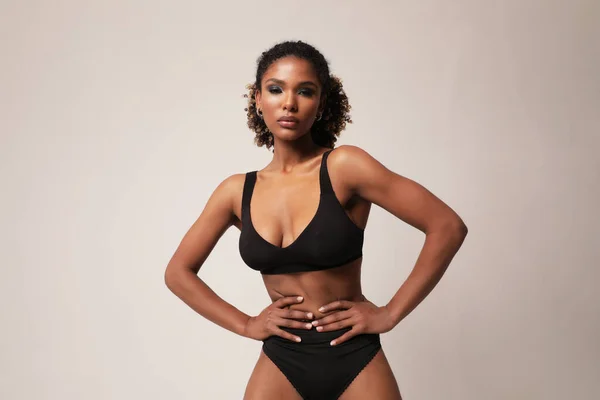 Afrikai amerikai fiatal nő tökéletes sportos test pózol fehér falon. — Stock Fotó