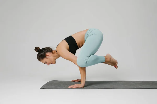 Ung koncentrerad kvinna gör yogaövningar balanserande på armarna. Modellering. — Stockfoto