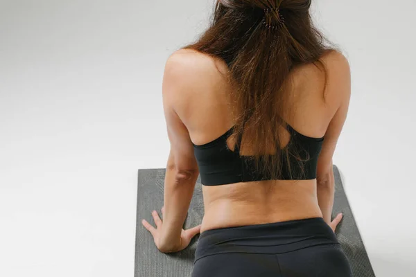 Vue arrière de la femme de yoga posant dans le studio blanc. Santé physique et mentale. — Photo