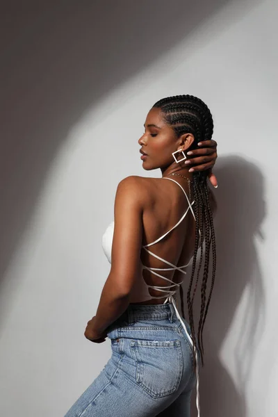 Side view portrait of African young woman with braids posing on grey background. — Stock Fotó