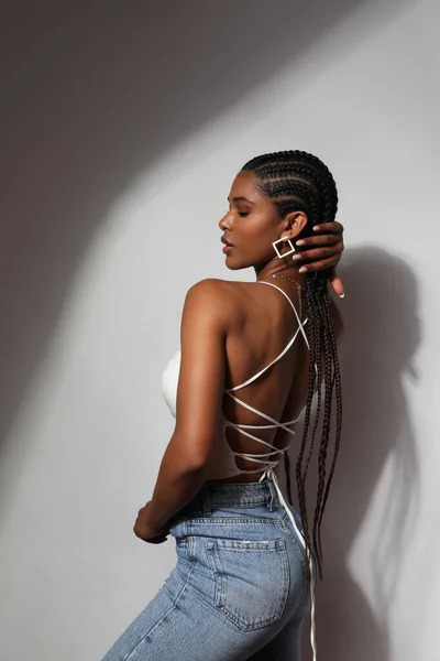 Side view portrait of African young woman with braids posing on grey background. — стокове фото