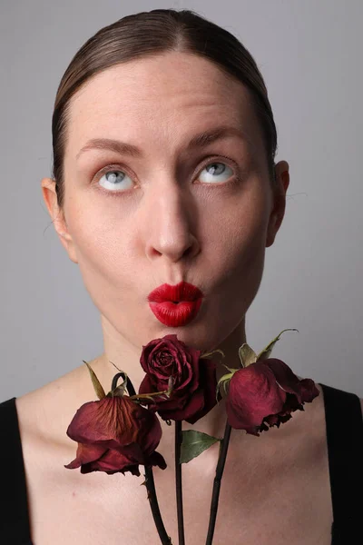 Retrato de mujer joven con rosas secas y mueca de la cara divertida. Vertical. —  Fotos de Stock