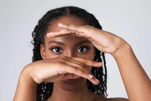 Close-up of African American woman covering her face with hand and poses indoor. — Stockfoto