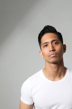 Beyaz duvarda poz veren yakışıklı Asyalı adam. Zihinsel konsept. Dikey maketleme.