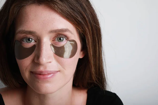 Debaixo de máscaras de olho de inchaço, dobras. Close-up de mulher aplicando manchas oculares. — Fotografia de Stock