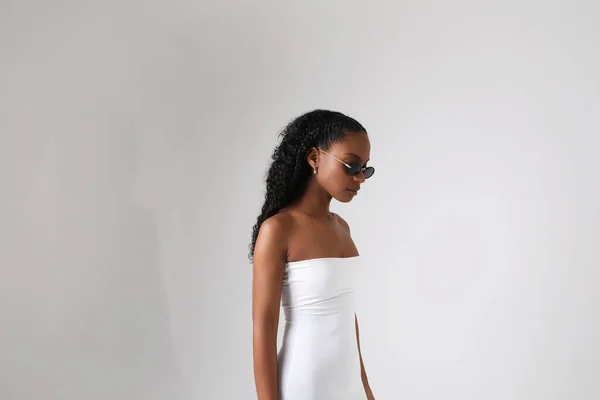 Gorgeous African American young woman wearing white dress posing in the studio. — Photo