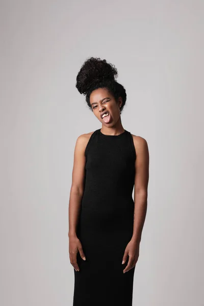 Young African American woman poses on white wall making face grimace. Vertical. — Stock Photo, Image