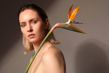Sarışın ve güzel bir kadının fotoğrafı egzotik çiçeklerle poz veriyor. Model.
