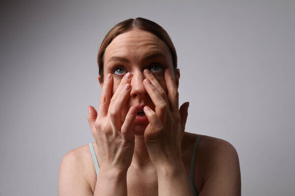 Головной укол молодой женщины касается ее глаз нетронутыми у нее глазная инфекция. Мак-ап