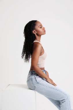 Genç bir kadın günlük giysiler giyer ve stüdyoda poz verir. Dikey. Yüksek kalite fotoğraf.