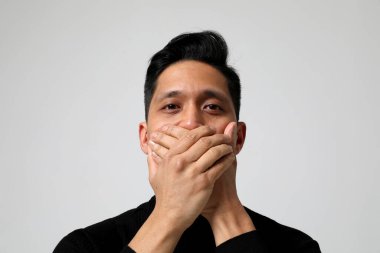 Asyalı adam ağzını kapatıp kameraya bakıyor. Akıl sağlığı sorunları. Yüksek kalite fotoğraf.