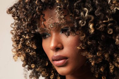Afro saçlı, kapalı alanda poz veren Afro-Amerikalı genç bir kadının dikey portresi. Yüksek kalite fotoğraf.