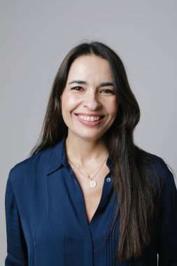 Beyaz duvarda poz veren mutlu, orta yaşlı bir kadının dikey portresi. Yüksek kalite fotoğraf.