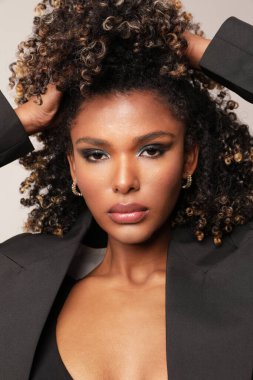 Vertical portrait of African American young woman with afro hair posing indoor. High quality photo.