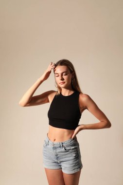 Hoş bir genç kız günlük giysiler giyiyor, içeride poz veriyor. Şefkatli, güzel. Yüksek kalite fotoğraf.