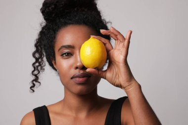 Beyaz arka planda limon meyvesiyle poz veren genç bir kadının yakın çekimi. Model-up. Yüksek kalite fotoğraf.