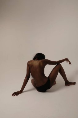 Back view of woman with long hair and perfect body posing against white wall. High quality photo. Mock-up.