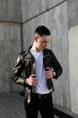Handsome smiling stylish hipster lambersexual model. Fashion male posing in the street. Vertical.