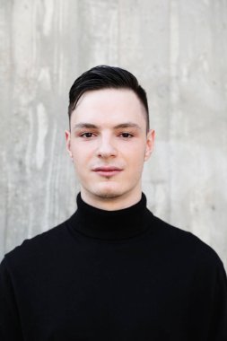 Handsome smiling stylish hipster lambersexual model. Fashion male posing in the street. Vertical.