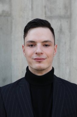 Handsome smiling stylish hipster lambersexual model. Fashion male posing in the street. Vertical.
