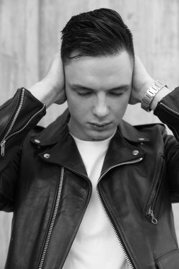 Yorgun adam dışarıda poz verirken deri ceket giyiyor. Dikey. Siyah ve beyaz. Yüksek kalite fotoğraf.