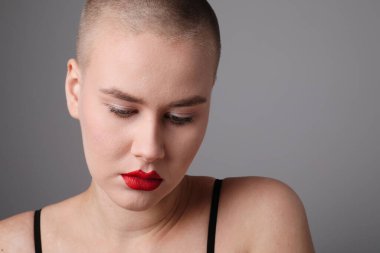 Açık gri arka planda poz veren güzel kel bir kadın. Model-up. Yüksek kalite fotoğraf.