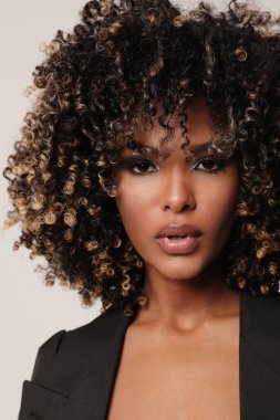 Afro saçlı, kapalı alanda poz veren Afro-Amerikalı genç bir kadının dikey portresi. Yüksek kalite fotoğraf.