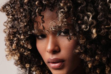 Afro saçlı, kapalı alanda poz veren Afro-Amerikalı genç bir kadının dikey portresi. Yüksek kalite fotoğraf.