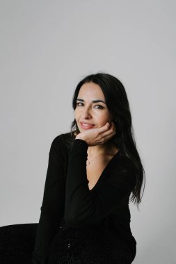 Beyaz duvarda poz veren mutlu, orta yaşlı bir kadının dikey portresi. Yüksek kalite fotoğraf.