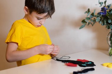 Çocuk dikiş işleriyle uğraşıyor. Keçeden yumuşak bir oyuncak dikmek, yakın plan eller. Evde zaman geçirmek..