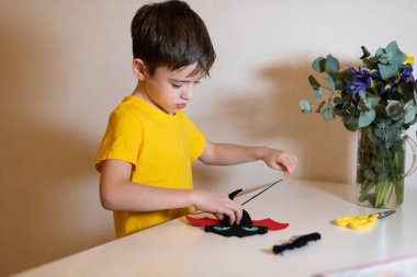 Çocuk dikiş işleriyle uğraşıyor. Keçeden yumuşak bir oyuncak dikmek, yakın plan eller. Evde zaman geçirmek..