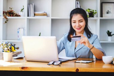 Çevrimiçi Alışveriş ve İnternet Ödemeleri, Asyalı kadın portresi kredi kartlarını ve dizüstü bilgisayarlarını online alışveriş yapmak veya dijital dünyada ayak işleri yapmak için kullanıyor.