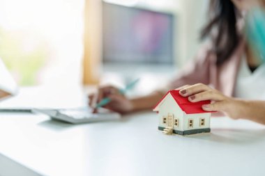 Girişimciler, iş sahipleri, muhasebeciler, emlakçılar, ev modelleri üzerine odaklanarak ev sahiplerinin finansal risklerini değerlendirmek için ev sermayesi hesap makineleri kullanan kadınlar..