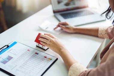 Girişimciler, iş sahipleri, muhasebeciler, emlakçılar, ev modelleri üzerine odaklanarak ev sahiplerinin finansal risklerini değerlendirmek için ev sermayesi hesap makineleri kullanan kadınlar..
