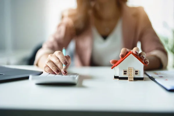 Girişimciler, iş sahipleri, muhasebeciler, emlakçılar, genç bir kadın emlak yatırımlarının risklerini hesaplamak için ev bütçesini hesaplamak için bir hesap makinesi kullanır..