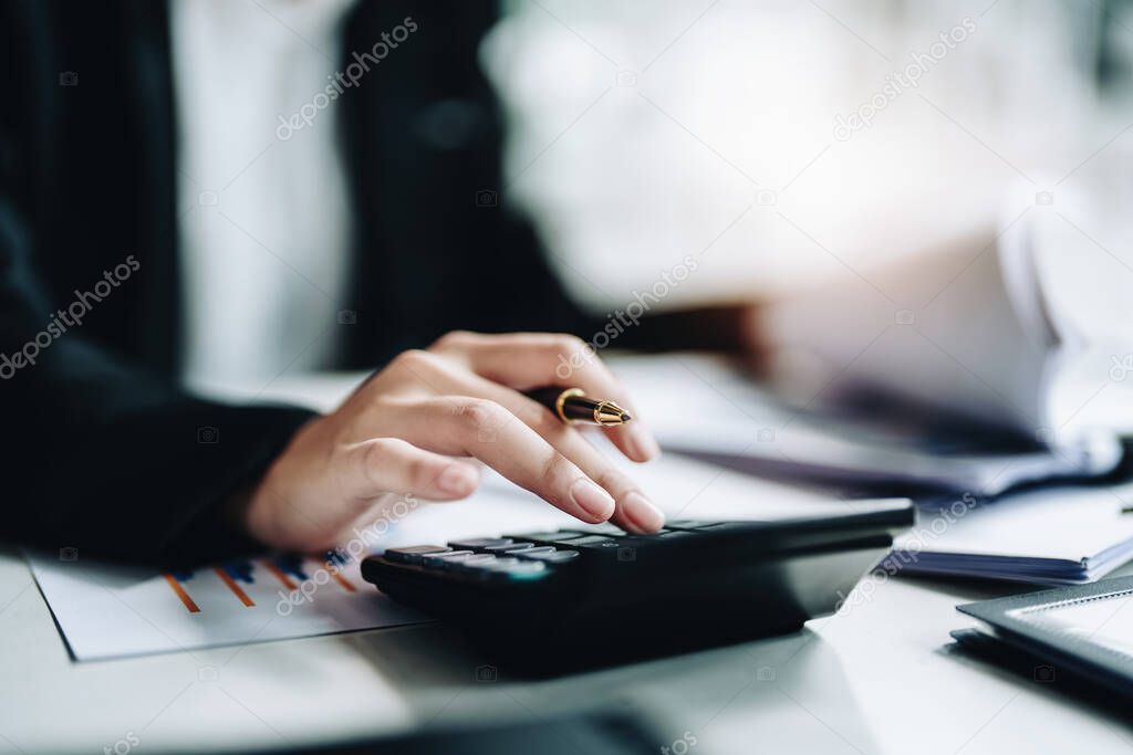 accountant, Auditor, Self-Employed, Finance and Investment, tax calculation and budget, Asian female entrepreneur using a calculator to calculate. Company business results document.