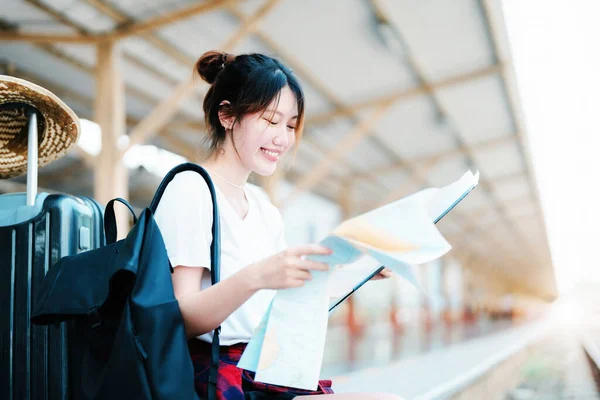 Summer, relax, vacation, travel, portrait of a cute Asian girl looking at a map to plan a trip while waiting at the train station. —  Fotos de Stock