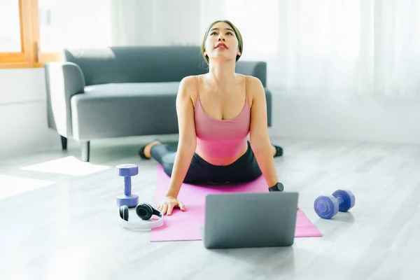 Sollievo dallo stress, rilassamento muscolare, esercizi di respirazione, esercizio fisico, meditazione, ritratto di giovane donna asiatica che rilassa il suo corpo dal lavoro d'ufficio praticando yoga guardando tutorial online. — Foto Stock