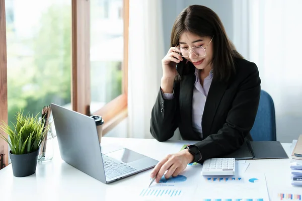 Affärskorrespondens, konsultation, porträtt av en asiatisk kvinna på telefon prata och planera bokslut och investeringar och använda datorer och dokument för att analysera finansiella system. — Stockfoto