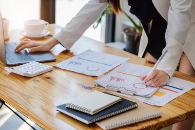 Genç ekonomistler veya muhasebeciler veya finansörler ve yatırımcılar bütçe belgelerini gözden geçiriyorlar ve kurumsal yatırım yönetimi üzerindeki etki ve risk değerlendirmelerini incelemek için bilgisayarları kullanıyorlar.