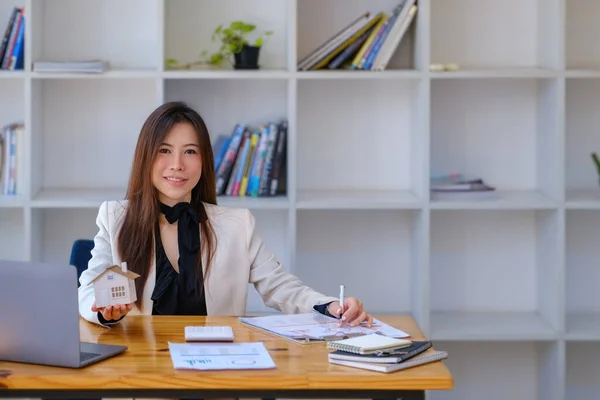 Mujer asiática contable, mujer de negocios, agente de bienes raíces, sosteniendo un bolígrafo, apuntando a los documentos de préstamo hipotecario y de intereses para calcular el riesgo en el presupuesto de inversión en el hogar. — Foto de Stock