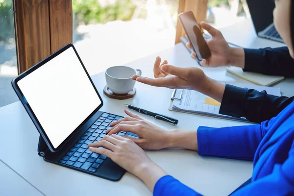 Una mujer de negocios que usa una tableta de pantalla blanca en blanco con una calculadora para calcular documentos presupuestarios en su escritorio — Foto de Stock